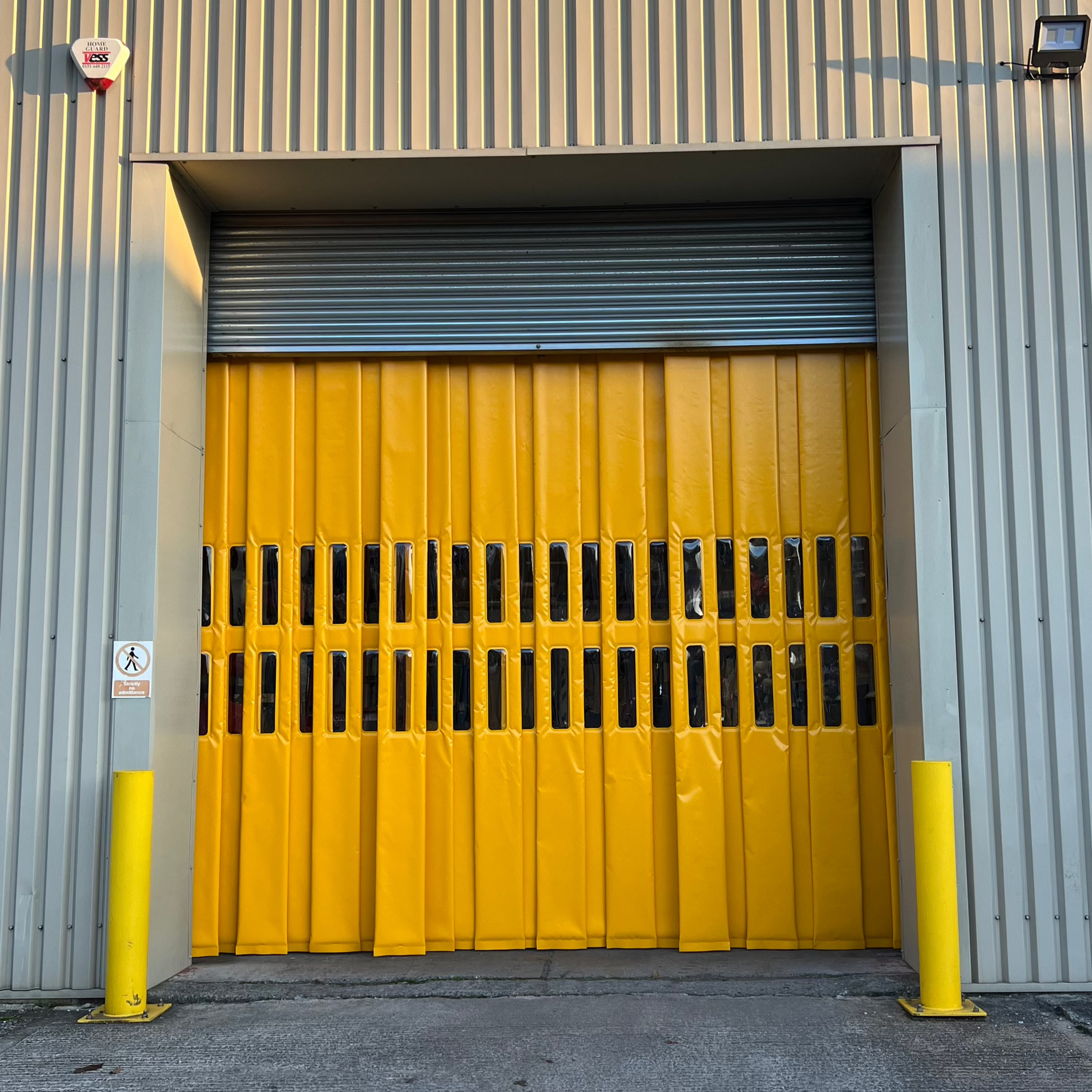 Koolshield™ yellow thermal strip curtain installed on an industrial roller door at a warehouse facility.