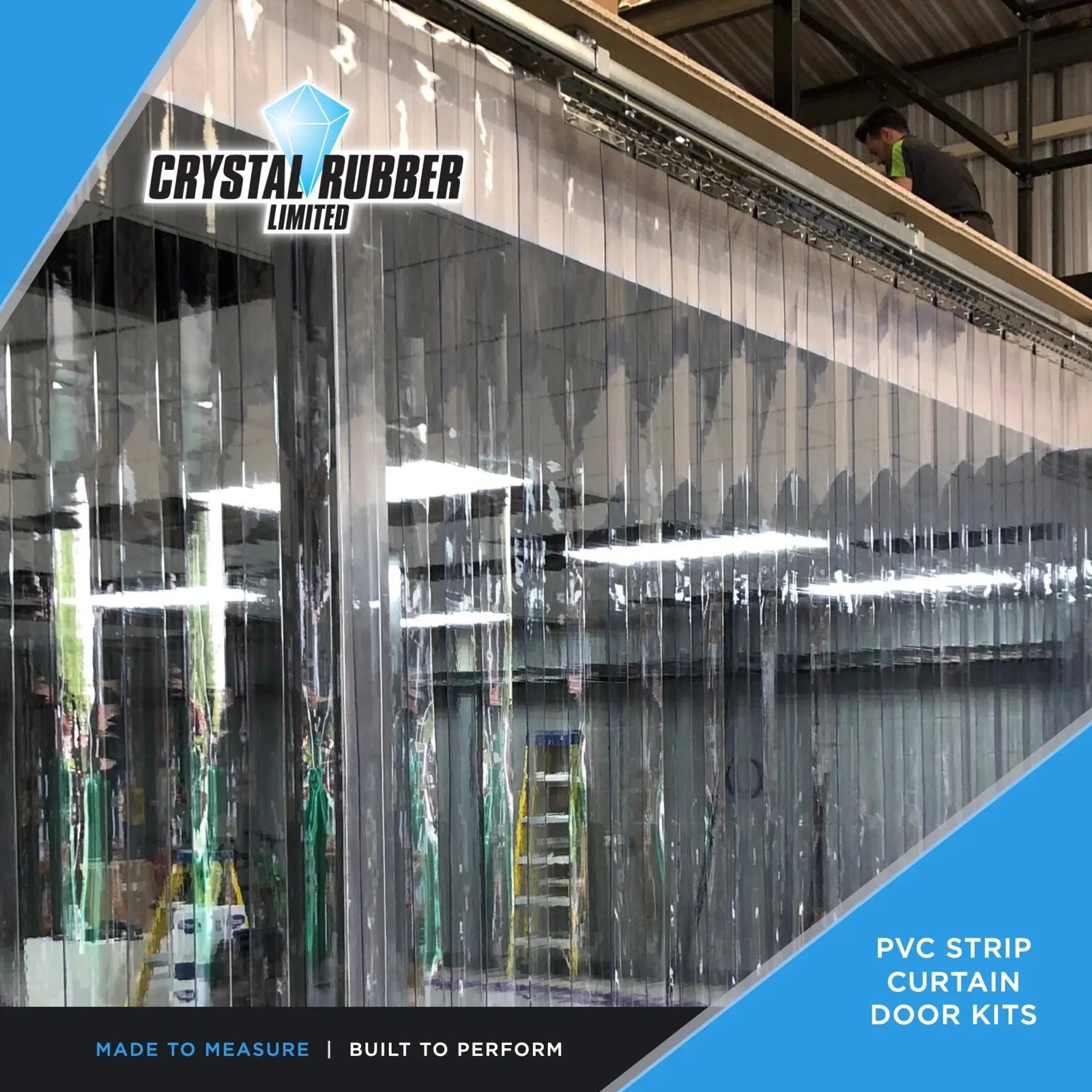 A long run of clear PVC strip curtain hanging from a stainless steel rail inside a warehouse